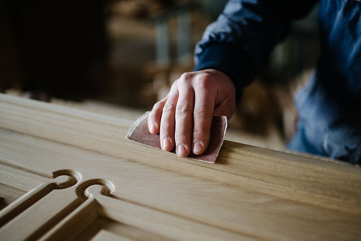 Hand prüft eine frisch geschliffene Holzoberfläche mit Nuten