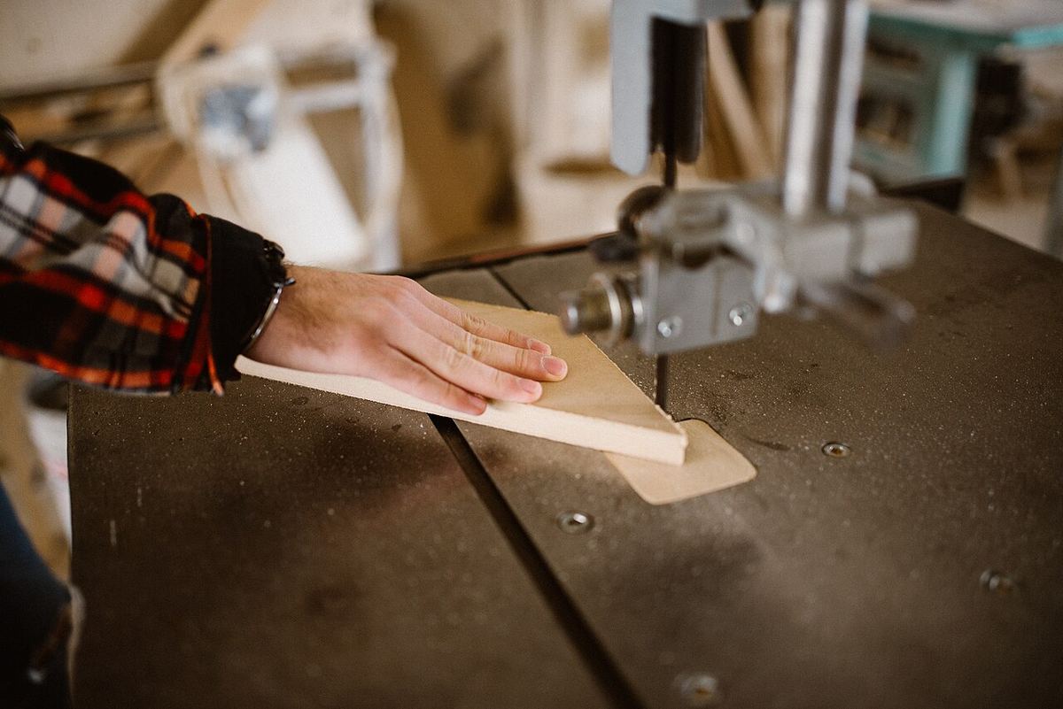 Hände führen ein Werkstück an einer Holzbearbeitungsmaschine